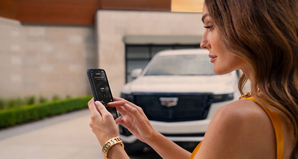 lady checking her mobile with a Cadillac vehicle background | Faulkner Cadillac Bethlehem in Bethlehem PA